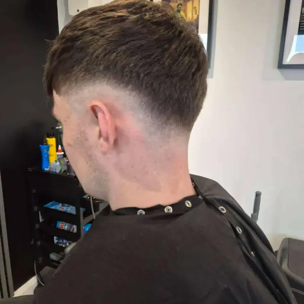 Mid skin fade with curly textured top, rear view