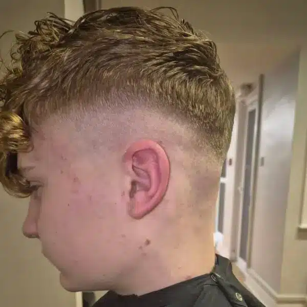 Mid skin fade with textured fringe, side view